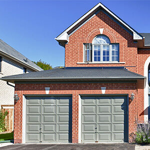 Brick two-story home with two gray garage doors.